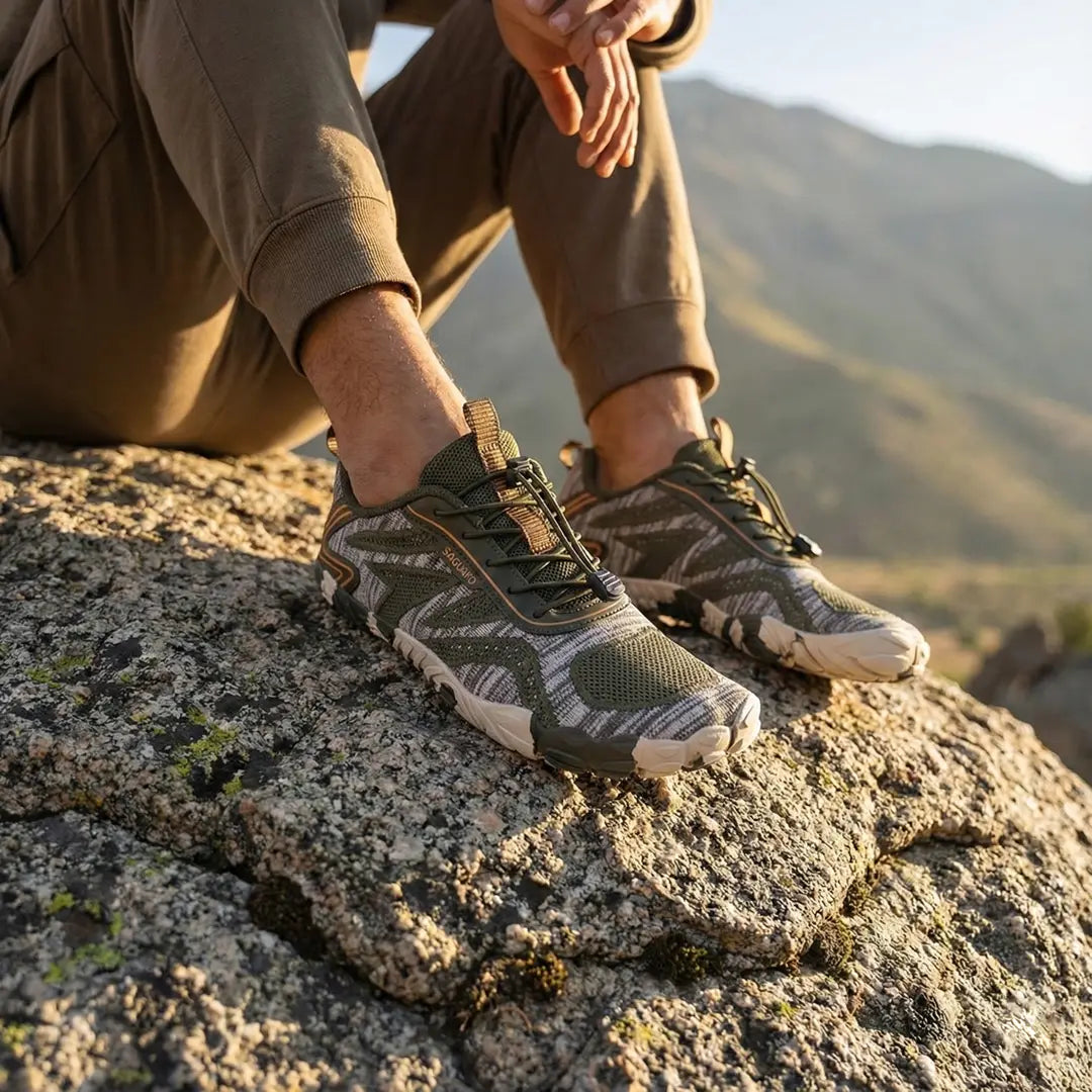 Hombre descansando sobre una priedra usando zapatos minimalistas verdes Saguaro Active II.