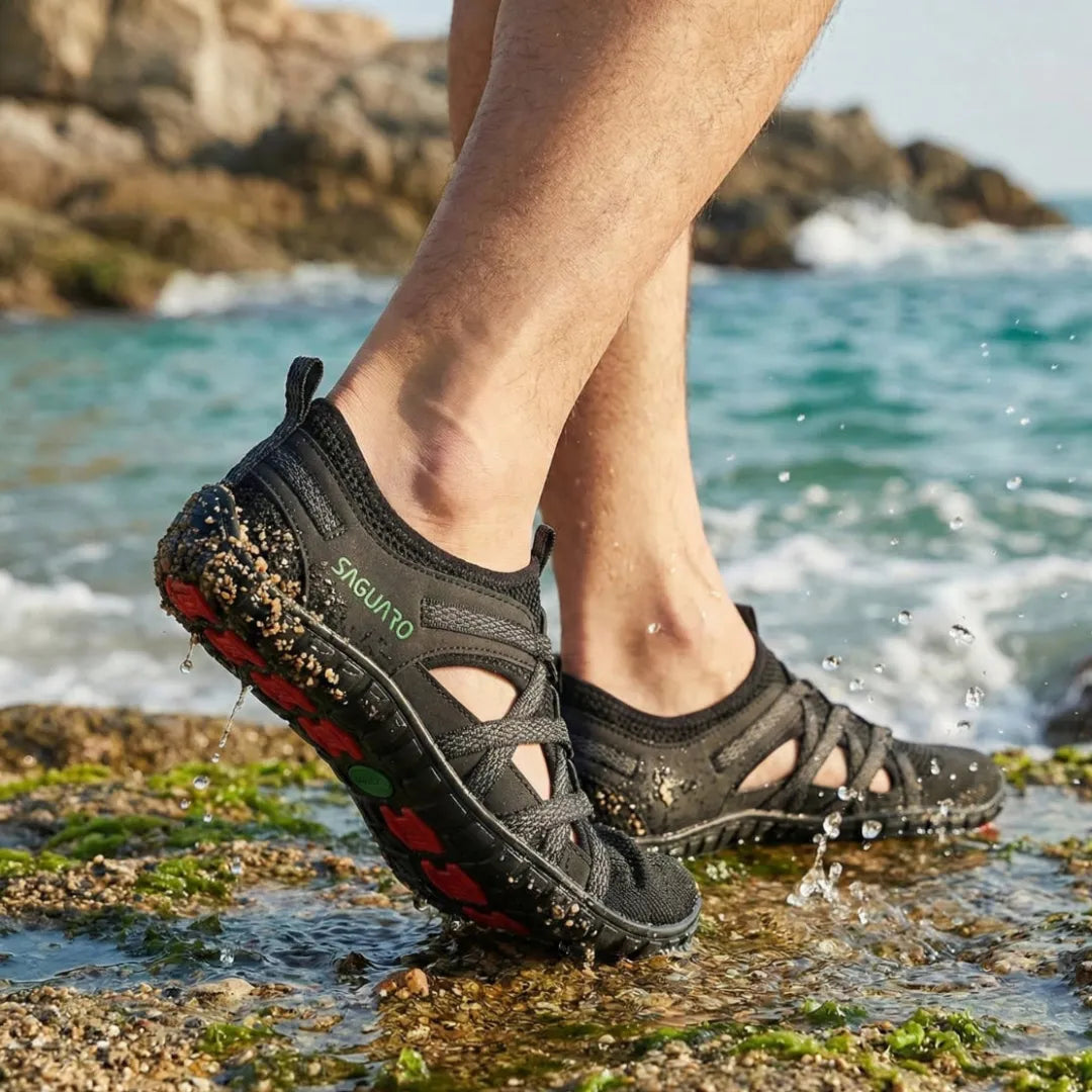 Pies en sandalias negras Breeze II en la playa