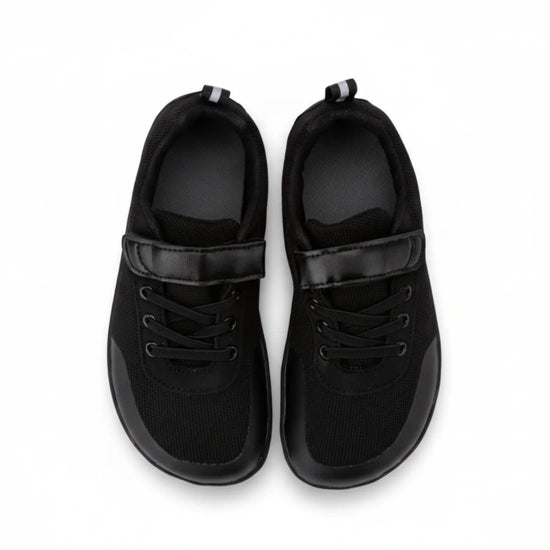 Bebe zapatillas negras con horma anatómica que permite el libre movimiento de dedos.