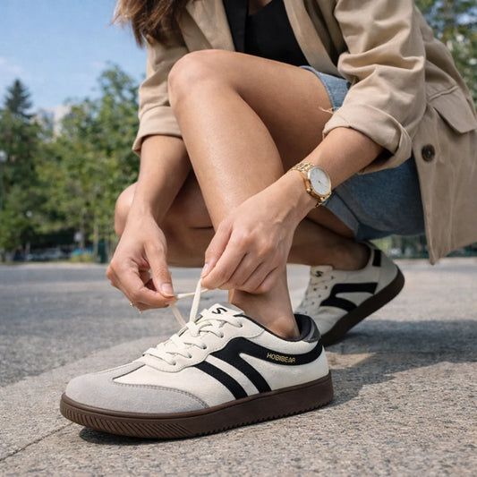 Mujer ajustando sus zapatillas barefoot en un entorno urbano, destacando comodidad y estilo.