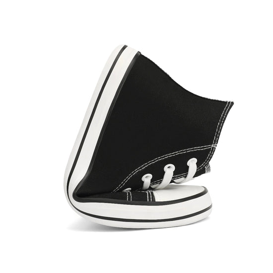 Zapatilla de lona negra doblada demostrando flexibilidad total de la suela.