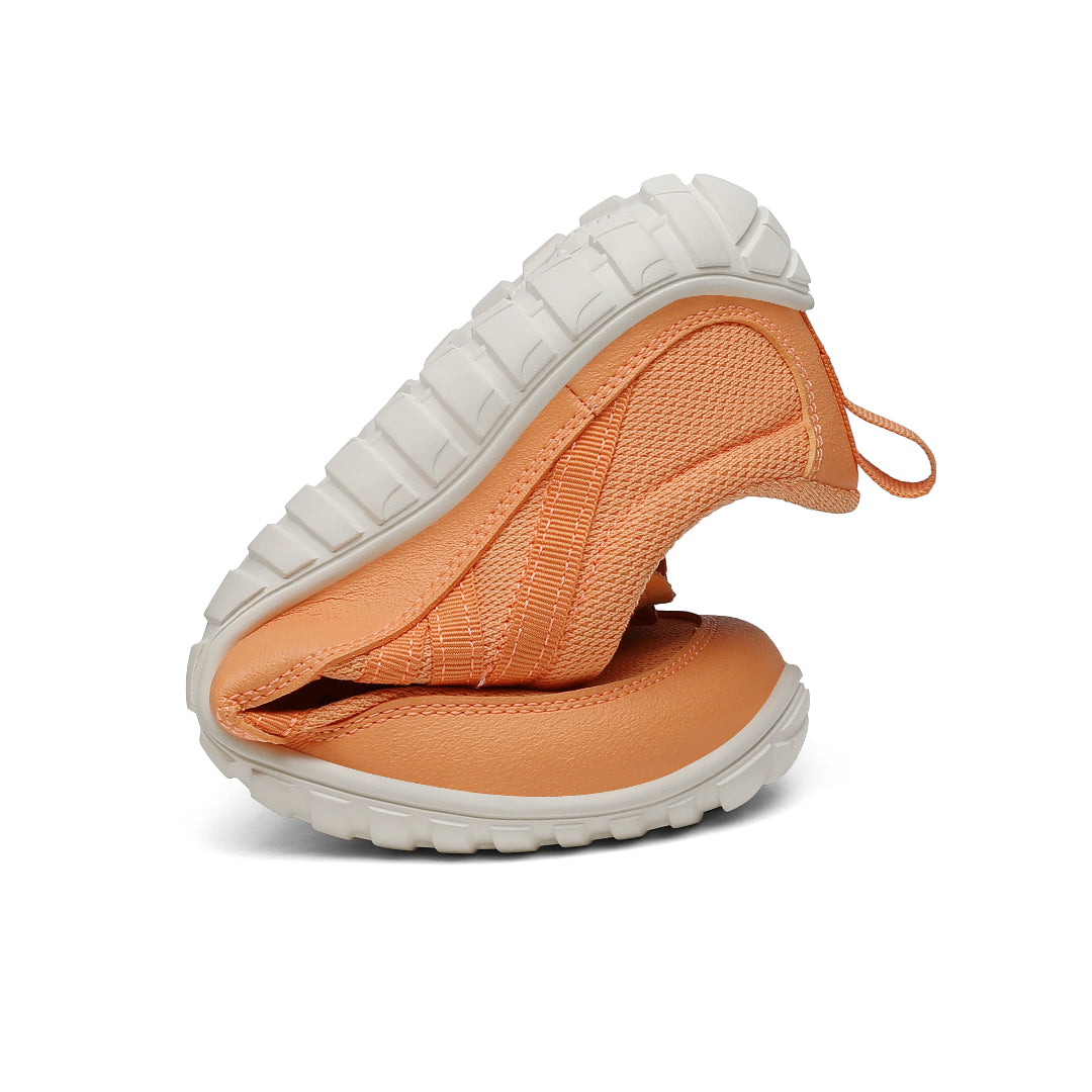 Zapatilla trail naranja doblada mostrando torsión y flexibilidad.