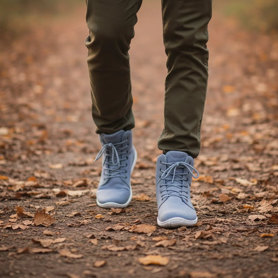 Hombre caminando sobre hojas secas con botas de invierno barefoot azules.