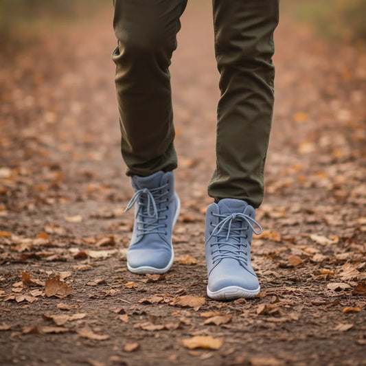 Hombre caminando sobre hojas secas con botas de invierno barefoot azules.
