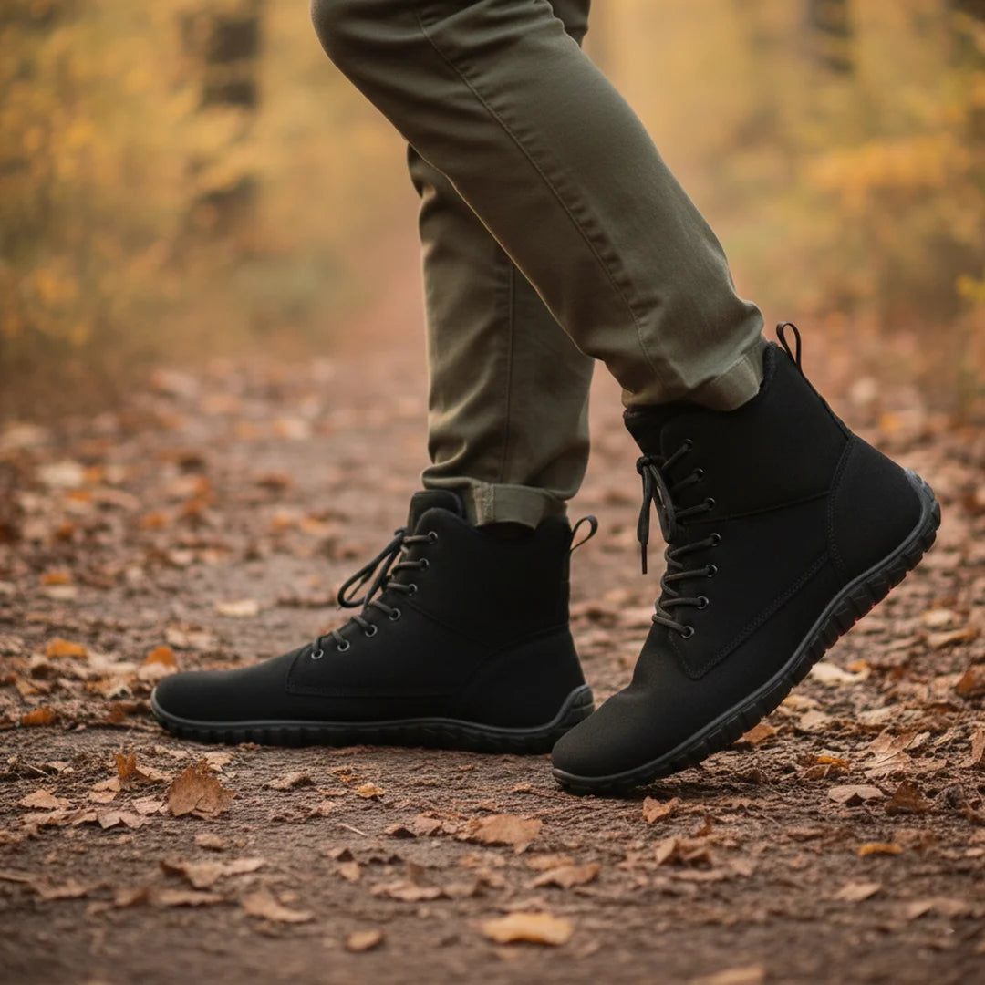 hombre caminando por sendero con hojas usando botas de invierno barefoot negras.