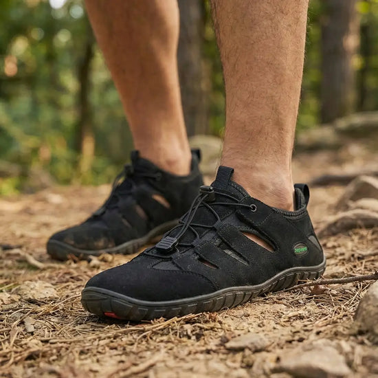 Hombre usando sandalias Saguaro Breeze I negras en sendero de bosque.