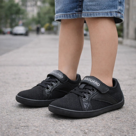 Zapatillas negras con velcro y cordones elásticos para un ajuste ergonómico y seguro.