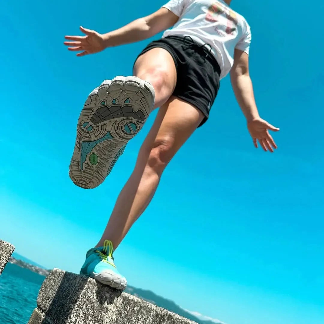 Mujer mostrando suela de zapatillas barefoot azul. 