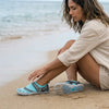 Mujer en la playa usando zapatillas de agua Saguaro celestes.