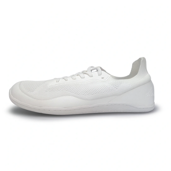 Perfil zapatilla deportiva minimalista blanca, suela plana.