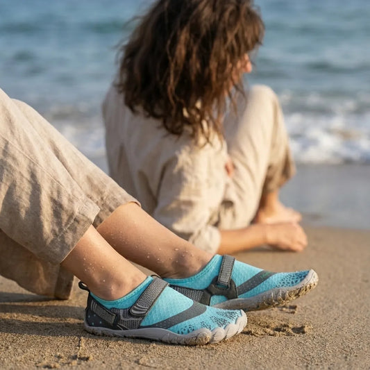 Mujer sentada en la arena usando zapatillas de agua Saguaro celestes.