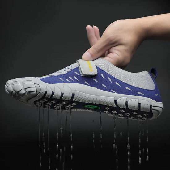 Mano sosteniendo zapatilla agua azul mostrando expulsión de agua por suela.