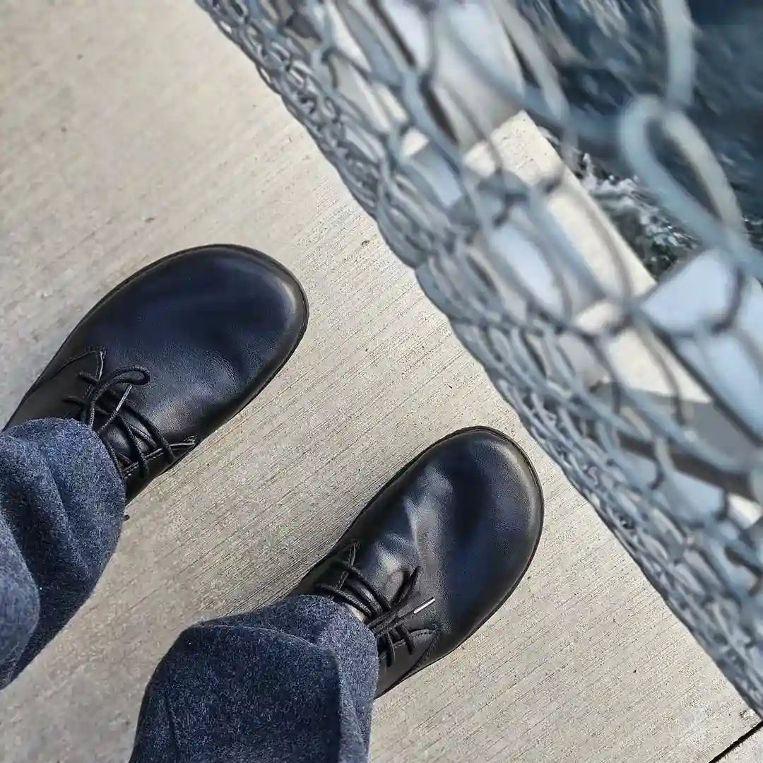 zapatos barefoot formales negros combinados con jeans en exterior