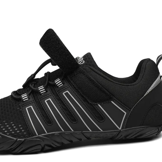 Detalle lateral de la zapatilla barefoot Saguaro Vigor II negra mostrando el cierre con velcro y materiales.