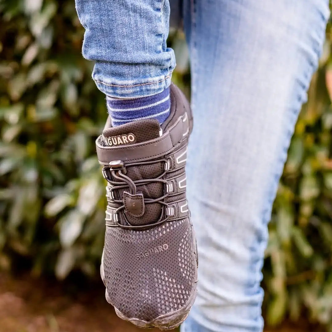 Persona usando zapatillas Saguaro Vigor II negras en exterior.