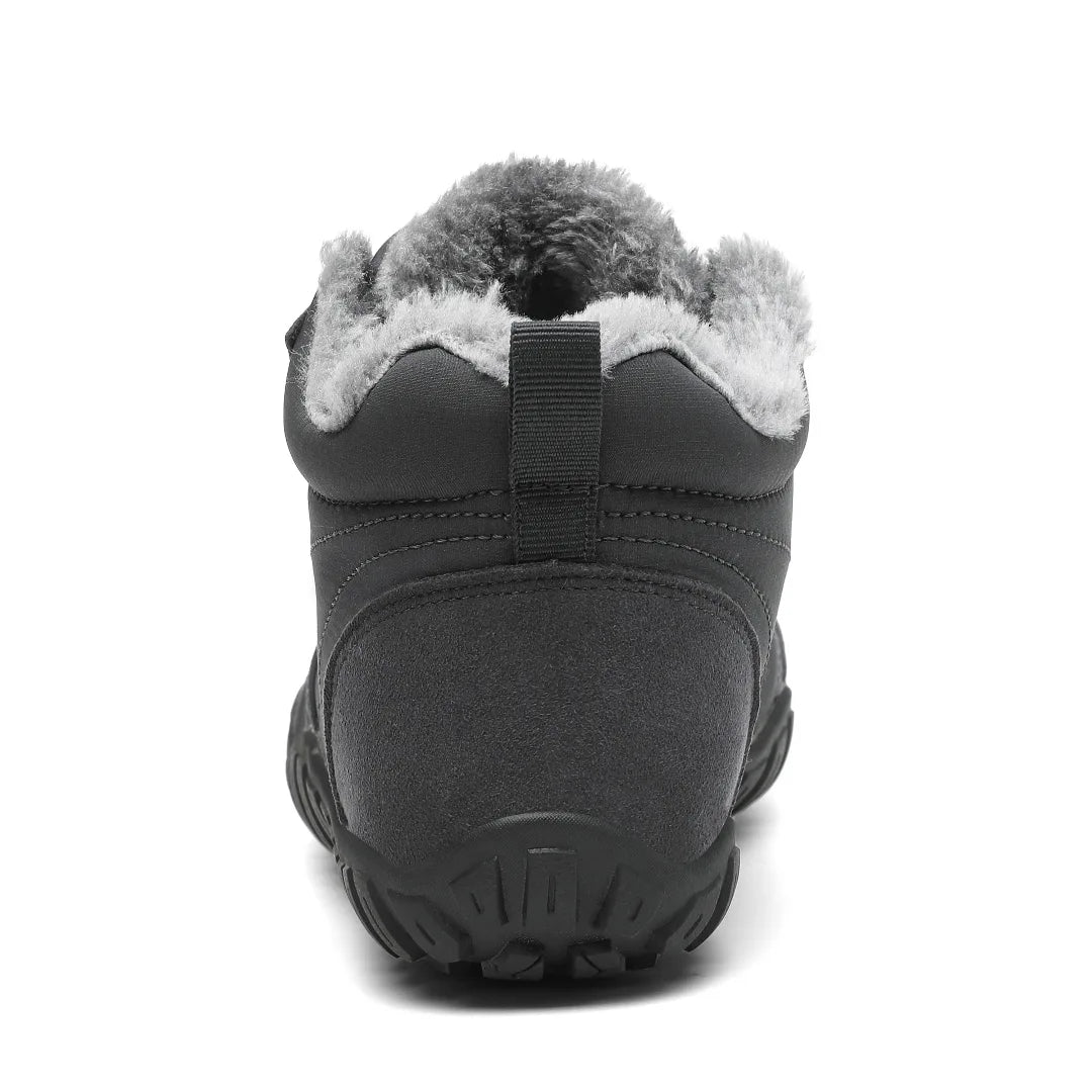 Vista trasera de la bota gris mostrando el diseño sin contrafuerte y suela plana.