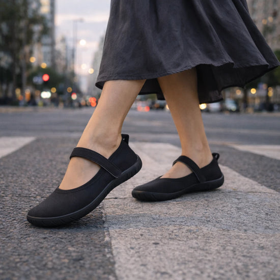 Mujer cruzando la calle con sandalias barefoot mujer tipo ballerinas negras de gran flexibilidad.