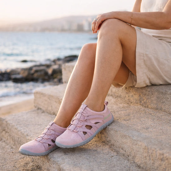 Mujer usando sandalias barefoot Breeze rosa en la playa.