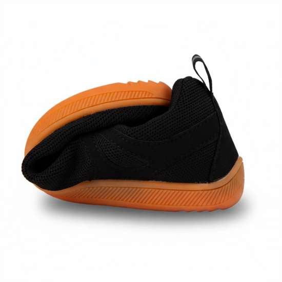 Zapatilla minimalista negra totalmente flexionada en una mano.