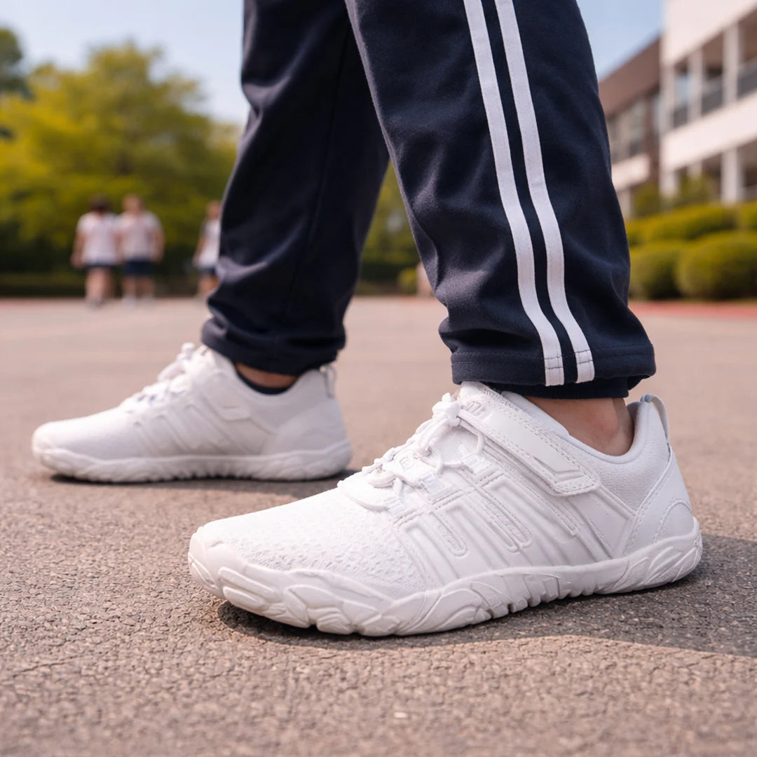 Niño realizando deportes con zapatillas blancas de educación física con diseño barefoot.