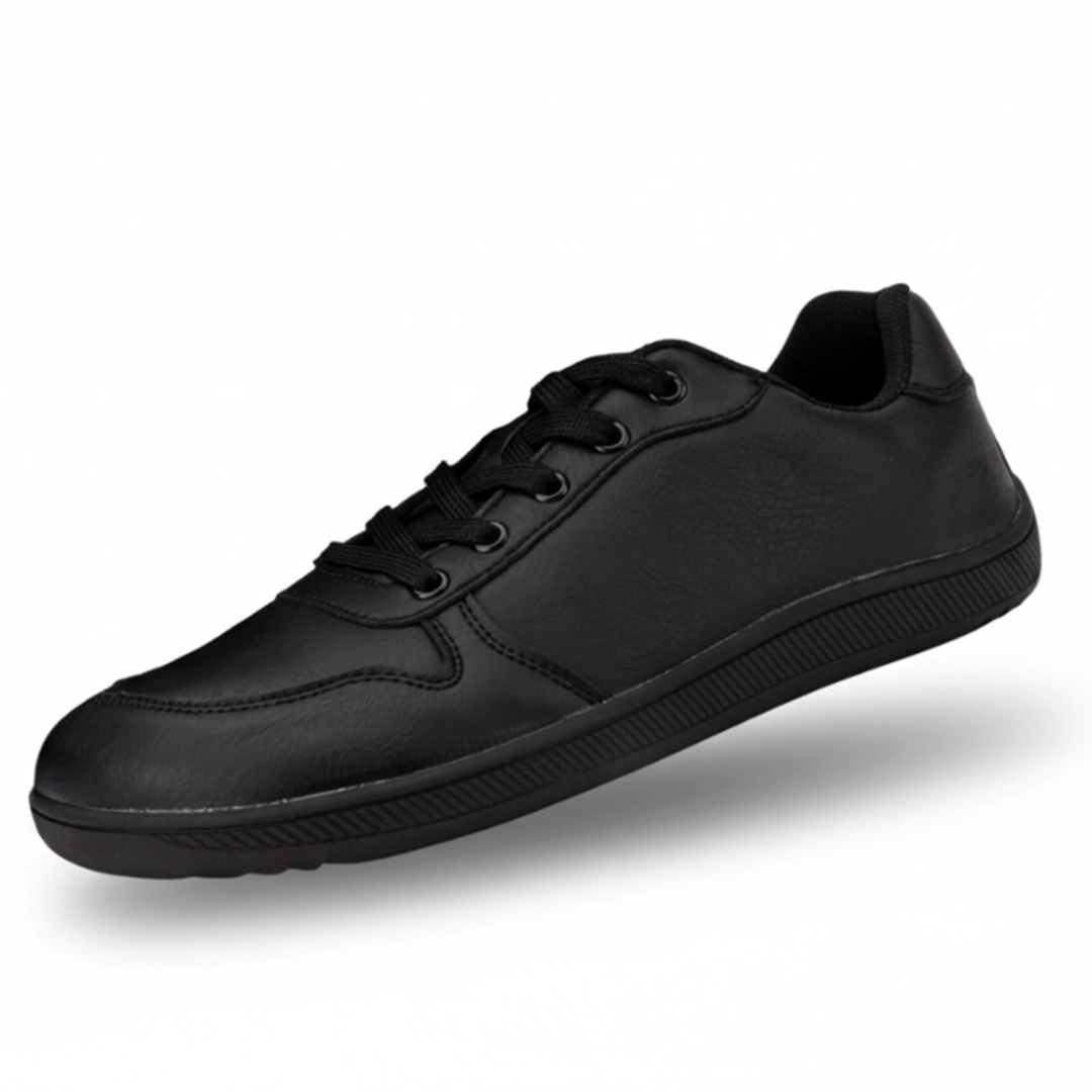 Zapatilla minimalista negra de piel sintética, estilo urbano y oficina.