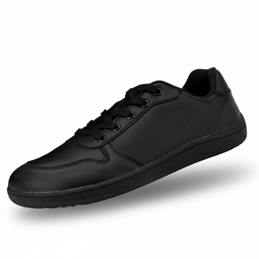 Zapatilla minimalista negra de piel sintética, estilo urbano y oficina.