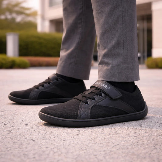 Zapato barefoot negro para niño con diseño de zapatilla urbana y suela plana.