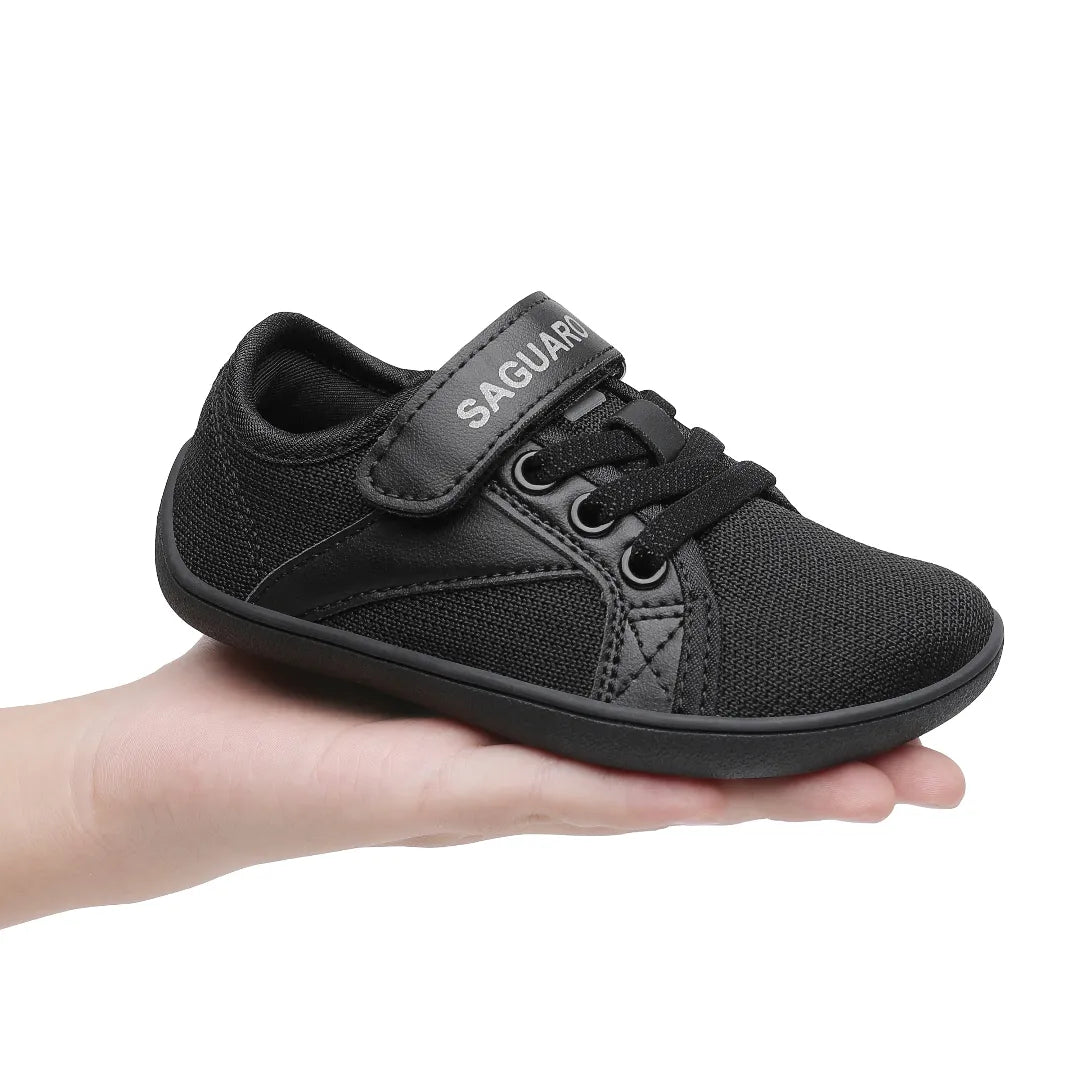 Calzado barefoot minimalista negro para niños, demostrado su peso ligero.