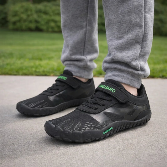 Zapatillas anchas infantiles negras con malla transpirable para actividad física escolar.