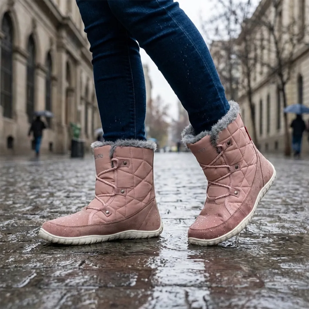 Mujer caminando sobre pavimento mojado usando zapatillas anchas impermeables Saguaro Rise I rosa.