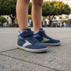 Niño caminando en una plaza usando zapatillas anchas infantiles Saguaro color azul.