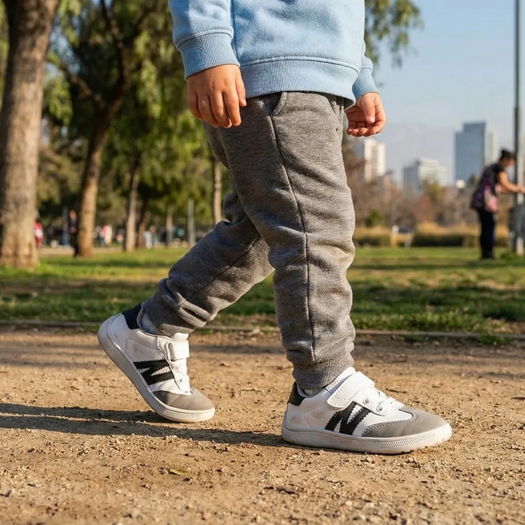 Niño caminando en el parque con zapatillas barefoot ZZFaber Kids Niza, mostrando la flexibilidad de la suela en pasto.