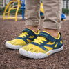 Niño jugando en la arena con zapatillas barefoot amarillas de alta visibilidad y flexibilidad.