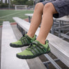 Niño sentado en el parque usando zapatillas barefoot verdes de malla transpirable.