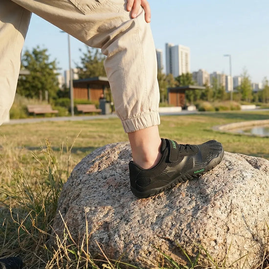 Niña con pie sobre roca usando zapatillas barefoot Saguaro Vitality III 2.0, destacando la tracción y flexibilidad de la suela en terrenos irregulares.