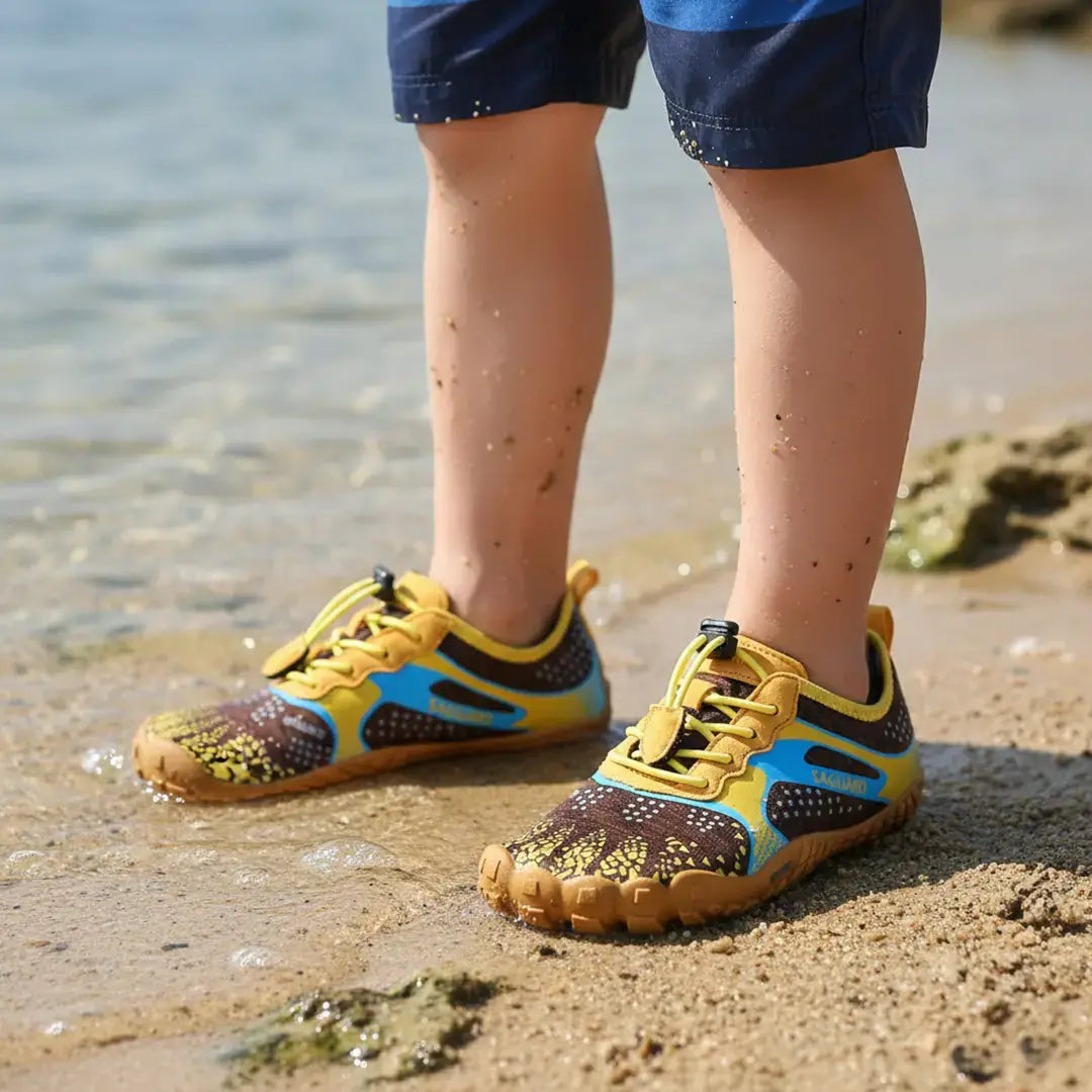 Niño Utilizando Zapatillas barefoot Saguaro Kids Fast I amarillas en la playa