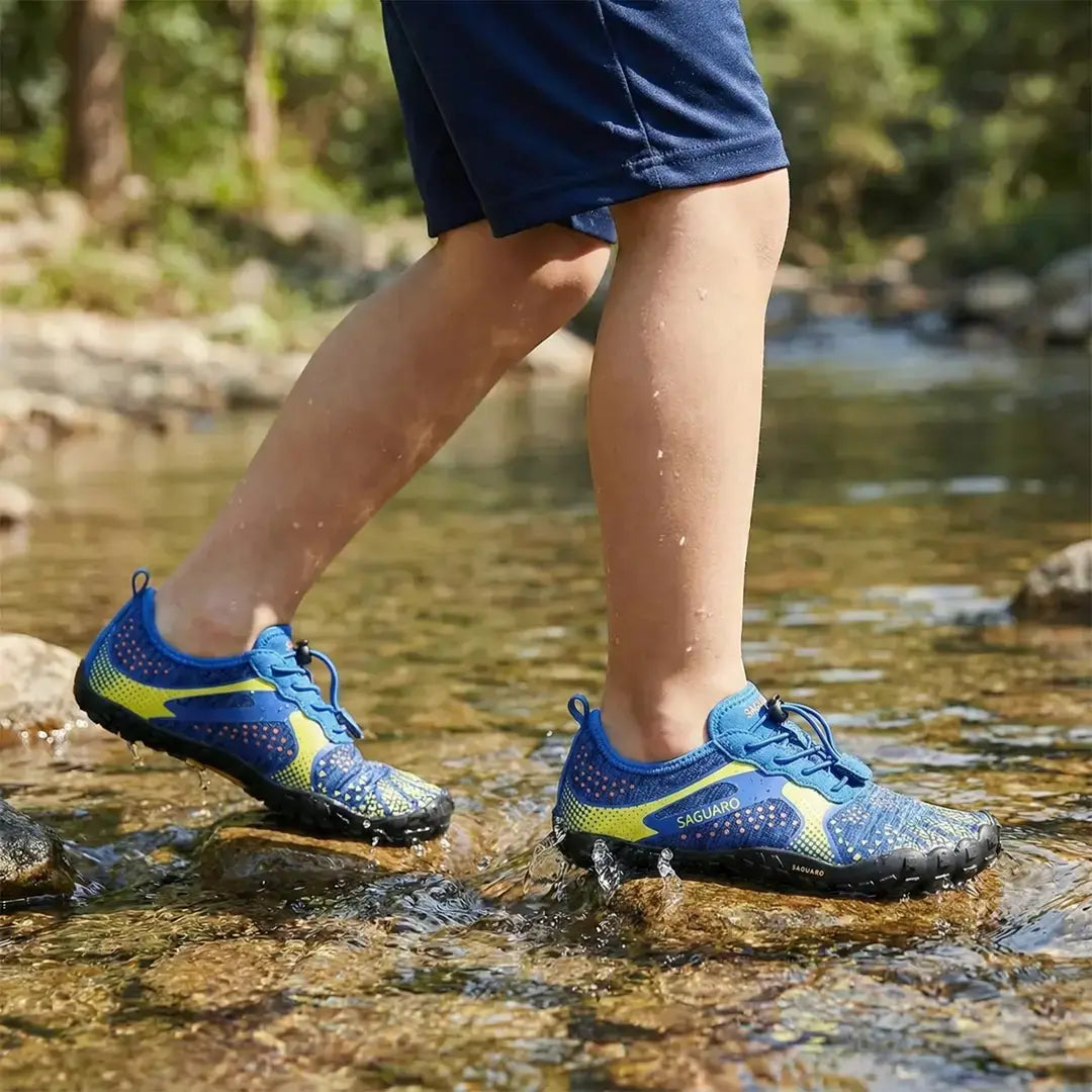 Niño utilizando Zapatillas barefoot Saguaro Kids Fast I amarillas en un río