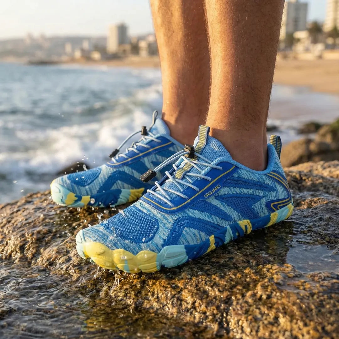 Persona de pie sobre rocas en la playa usando zapatillas azules Saguaro Active II.