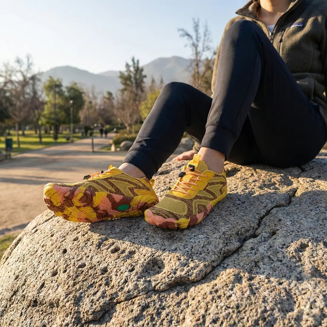 Persona descansando en una roca de gran tamaño usando zapatillas amarillas Saguaro Active II.